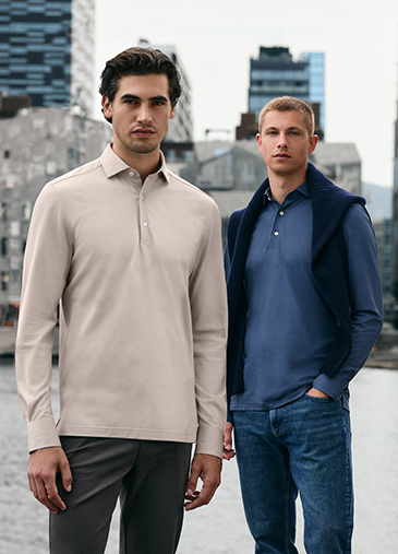 Model in einem weißen T-Shirt, hellblauen Jeans und grauen Schuhen vor einem beigen Hintergrund.